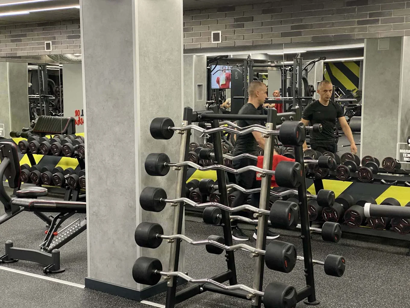 Зона свободни тежести с уретанови дъмбели и стелаж с лостове в City Group Fitness Club