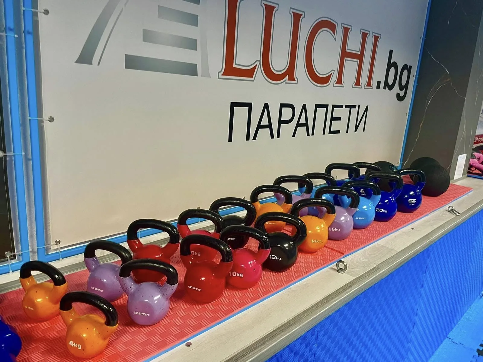 Винилови kettlebells SZ Sport 4–24 кг подредени в редица