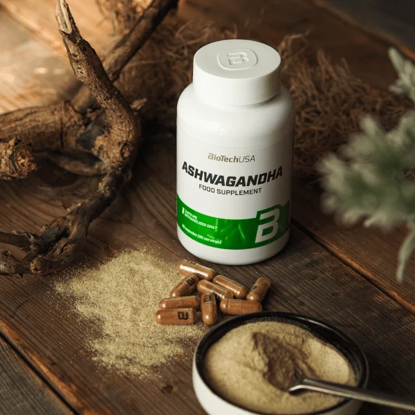 Опаковка BioTech USA Ashwagandha заедно с няколко капсули, поставени до нея, вероятно с чаша вода, символизираща приема.