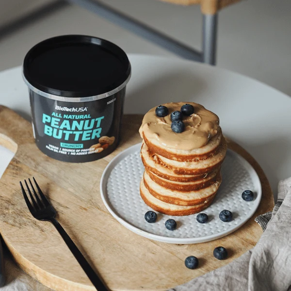 Отворена опаковка BioTech USA Peanut Butter Crunchy, показваща хрупкавата текстура с парченца фъстъци.