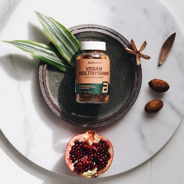 Опаковка BioTech USA Vegan Multivitamin на фона на спортна екипировка