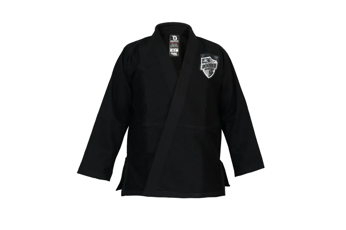 Детайлна снимка на якето на черното BJJ кимоно Booster V 2 PRO SHIELD BLACK, показваща текстурата на плата, контрастните шевове и логото.