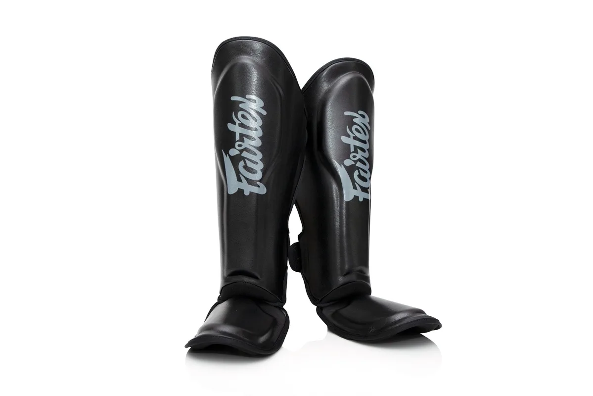 Черни протектори за крака Booster FXB SG, изглед отпред, с ясно видими лога на Fairtex и Booster.