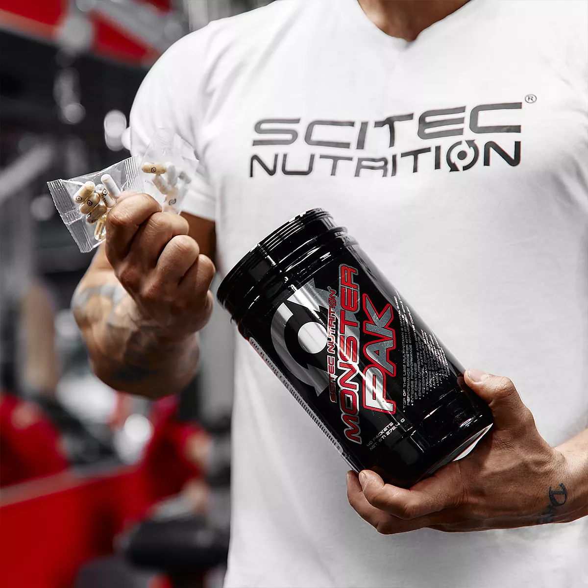 Близък план на един дневен пакет Scitec Nutrition Monster Pak, съдържащ различни капсули и таблетки.