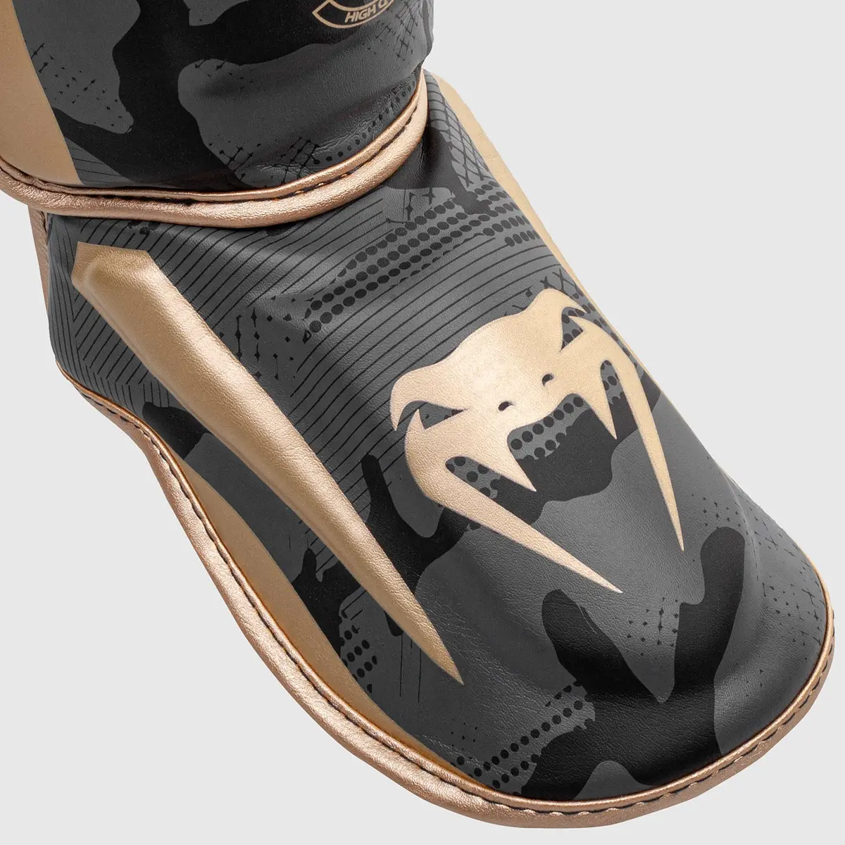 Venum Elite Shin Guard - Gold Camo детайлен изглед на предната част и емблемата